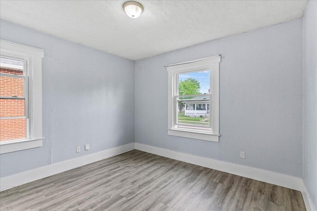 empty room featuring baseboards, a textured ceiling, and wood finished floors