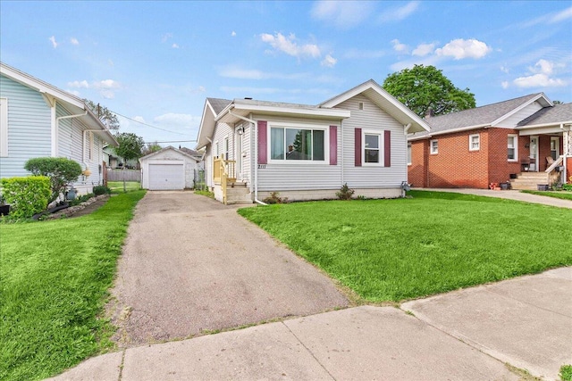 bungalow-style house featuring a garage, a front lawn, aphalt driveway, and an outbuilding