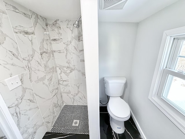 bathroom featuring toilet and a tile shower