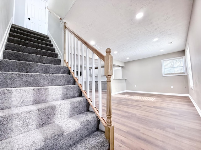 stairs with hardwood / wood-style flooring and a textured ceiling