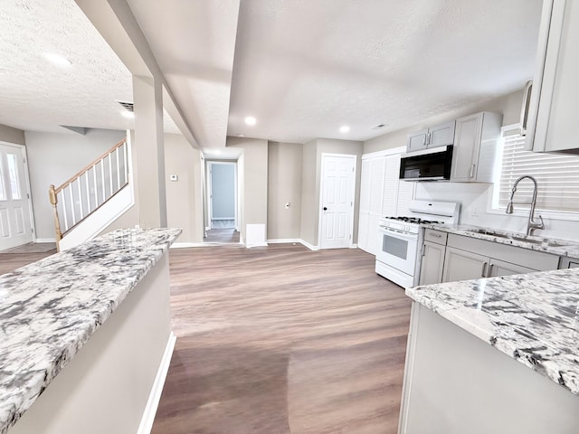 kitchen with sink, gray cabinets, light stone countertops, a textured ceiling, and white gas range