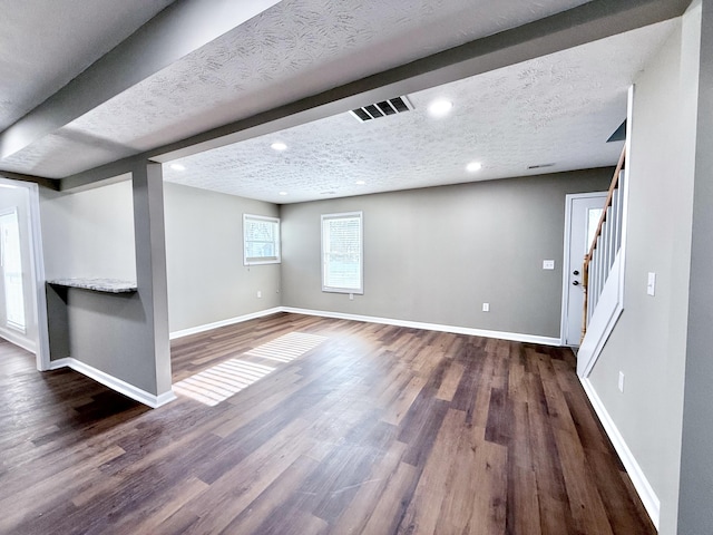 basement featuring dark hardwood / wood-style flooring and a textured ceiling