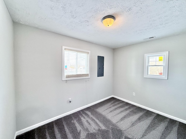 carpeted spare room featuring electric panel and a textured ceiling