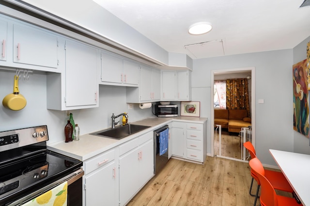 kitchen with radiator heating unit, white cabinetry, sink, light hardwood / wood-style floors, and stainless steel appliances