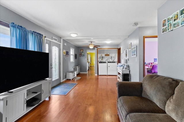 living area featuring light wood-type flooring, radiator, ceiling fan, and washer and clothes dryer
