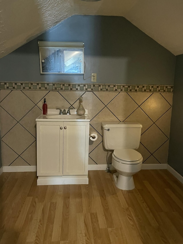 1211 N Lowry Ave, Springfield, OH 45504 - half bathroom featuring vanity, wood finished floors, vaulted ceiling, and tile walls