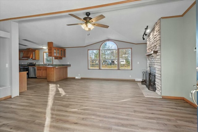 unfurnished living room featuring light hardwood / wood-style floors, vaulted ceiling, ceiling fan, and a stone fireplace