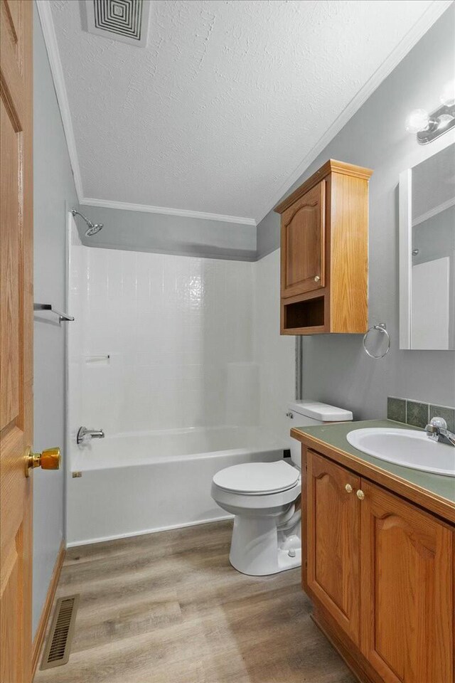 full bathroom with bathtub / shower combination, hardwood / wood-style flooring, toilet, a textured ceiling, and vanity