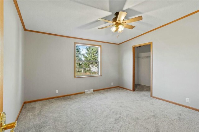 unfurnished bedroom featuring ceiling fan, crown molding, carpet floors, and a closet