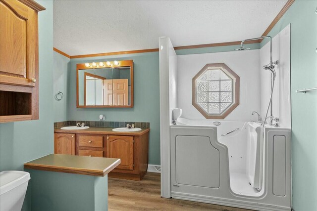 bathroom with hardwood / wood-style flooring, ornamental molding, toilet, a textured ceiling, and vanity