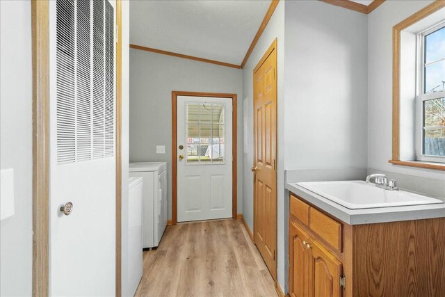 laundry room with ornamental molding, sink, light hardwood / wood-style floors, and independent washer and dryer