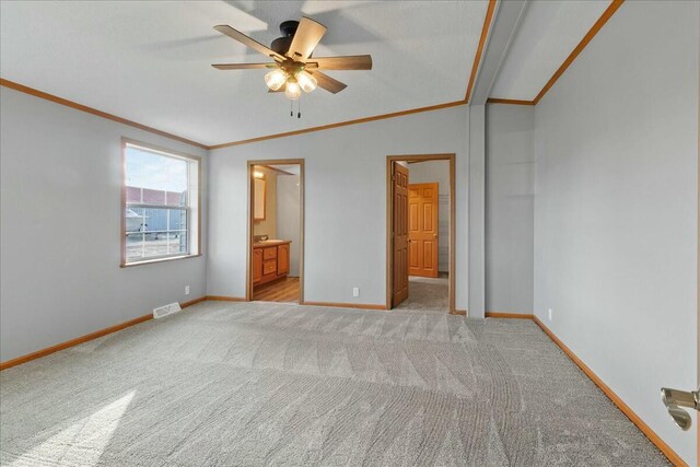 unfurnished bedroom with ensuite bath, crown molding, light colored carpet, and lofted ceiling