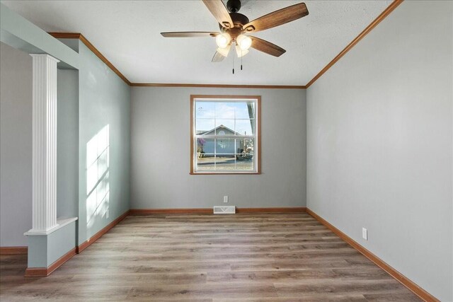 empty room with ceiling fan, light hardwood / wood-style flooring, crown molding, and ornate columns