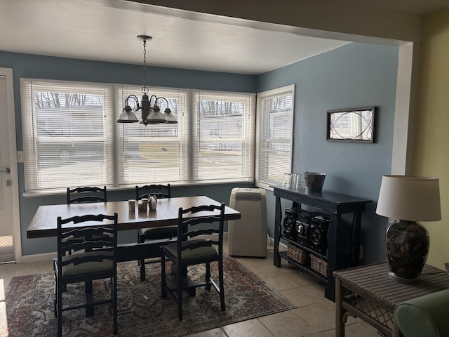 dining space with light tile patterned floors, a chandelier, and baseboards