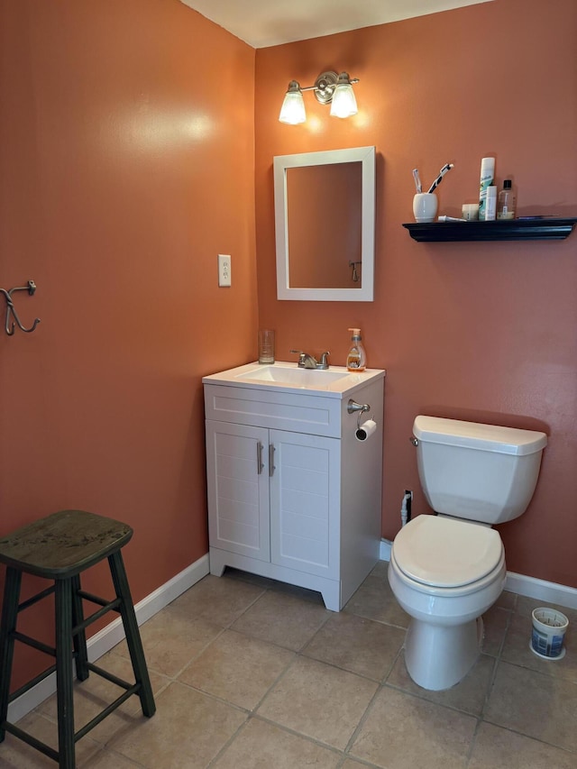 half bathroom with tile patterned floors, toilet, vanity, and baseboards
