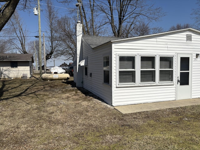 view of side of home featuring roof with shingles and a chimney