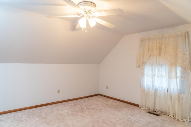 bonus room featuring lofted ceiling, light colored carpet, visible vents, baseboards, and a ceiling fan