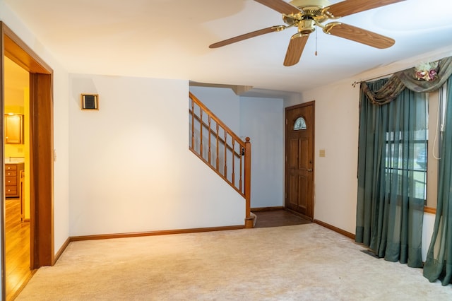 foyer entrance featuring light carpet, stairs, and baseboards