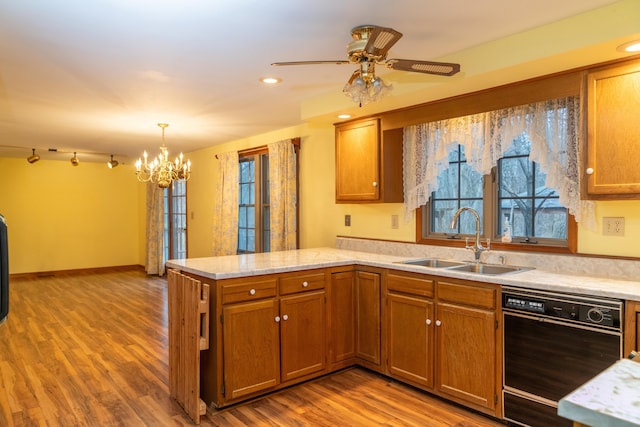 kitchen featuring black dishwasher, brown cabinets, a sink, and a peninsula