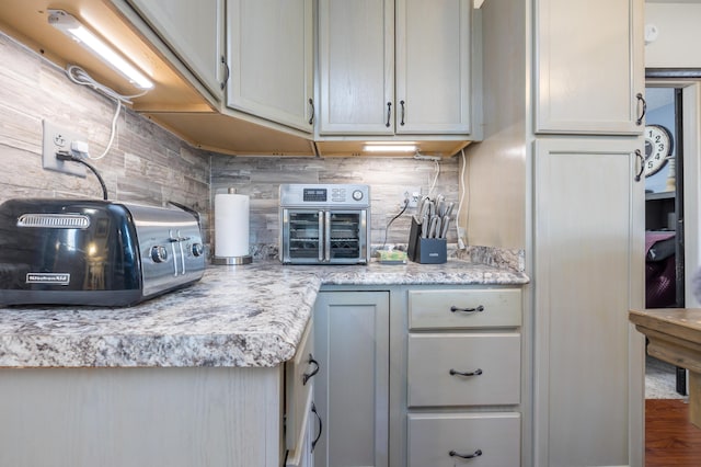 kitchen featuring light stone counters, a toaster, and backsplash