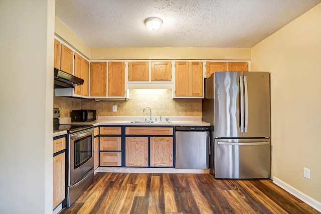 kitchen with dark wood-type flooring, sink, a textured ceiling, stainless steel appliances, and decorative backsplash