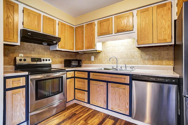 kitchen with appliances with stainless steel finishes, sink, backsplash, and dark hardwood / wood-style floors