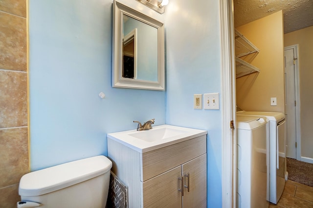 bathroom featuring tile patterned flooring, vanity, a textured ceiling, separate washer and dryer, and toilet