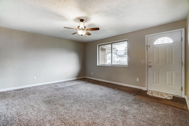 foyer entrance featuring ceiling fan, carpet floors, and a textured ceiling