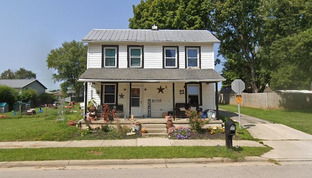 view of front facade with a porch, fence, a front yard, and metal roof