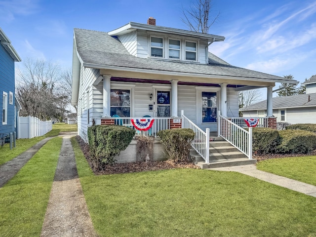 bungalow-style home with driveway, roof with shingles, a porch, and a front yard