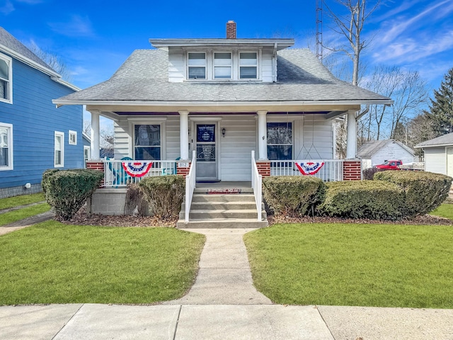 bungalow-style house featuring a front yard, a porch, roof with shingles, and a chimney