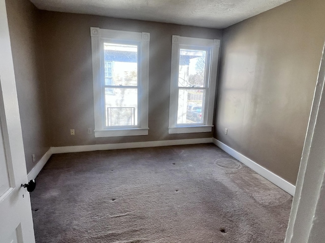 carpeted empty room featuring a textured ceiling and baseboards