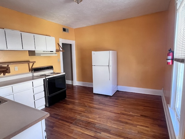 kitchen featuring visible vents, white cabinets, range with electric stovetop, and freestanding refrigerator