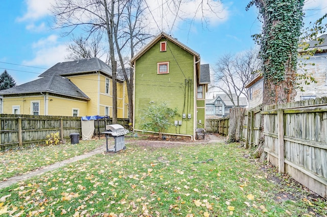 rear view of house with a yard and a fenced backyard