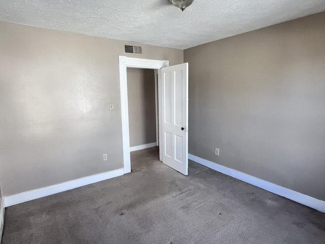 unfurnished bedroom with carpet, a textured ceiling, visible vents, and baseboards