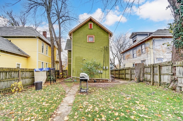 rear view of property with fence and a lawn