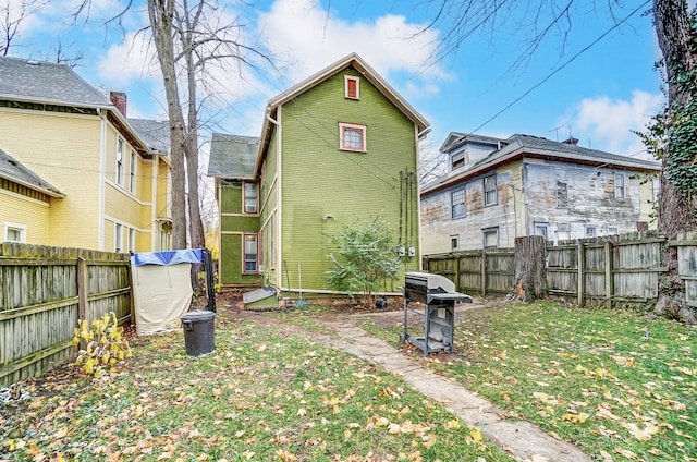 back of property featuring fence and a lawn