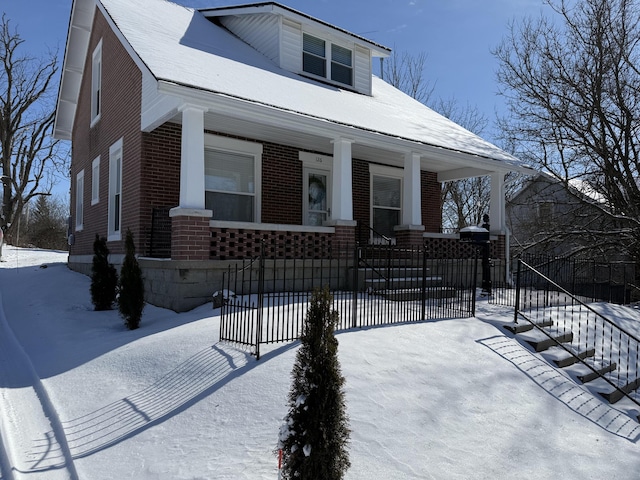 bungalow-style home featuring covered porch and brick siding