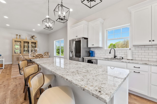 kitchen with a center island, a sink, stainless steel appliances, recessed lighting, and white cabinetry