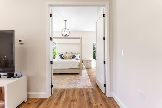 bedroom with baseboards, a chandelier, and wood finished floors