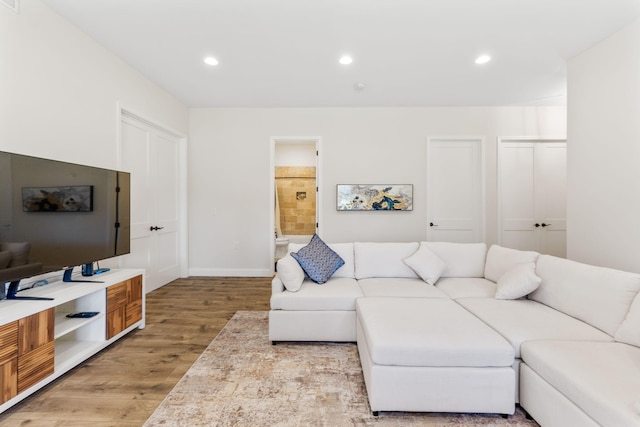 living room with recessed lighting, baseboards, and light wood-type flooring