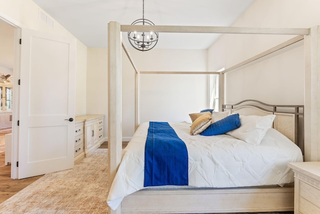 bedroom with an inviting chandelier, light wood-style floors, and visible vents