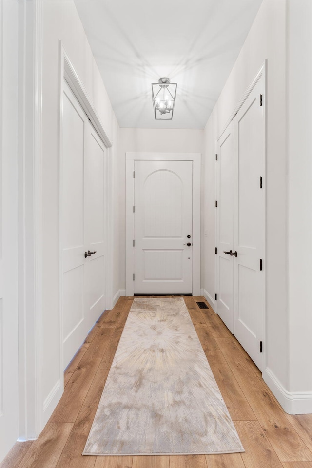 entryway with an inviting chandelier, baseboards, and light wood finished floors