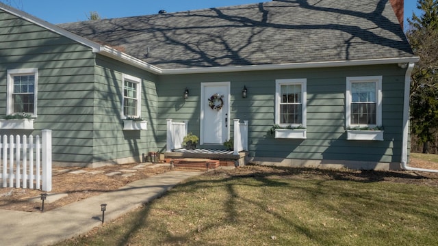 view of front of house with a front lawn, fence, roof with shingles, and a chimney