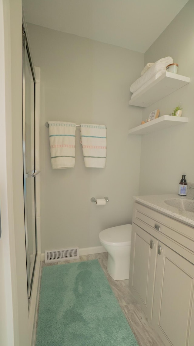 full bathroom featuring vanity, toilet, visible vents, and a stall shower