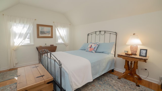 bedroom with baseboards, lofted ceiling, and wood finished floors