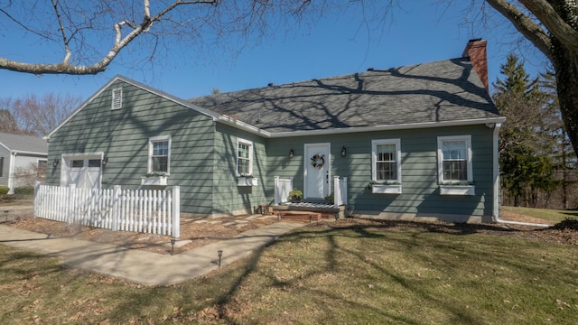 view of front facade featuring a chimney, roof with shingles, a front lawn, and fence