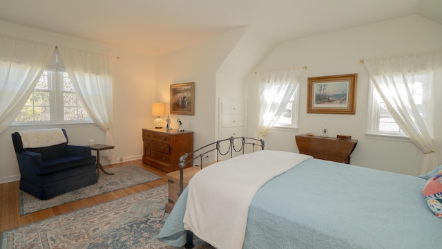 bedroom with vaulted ceiling, multiple windows, and wood finished floors