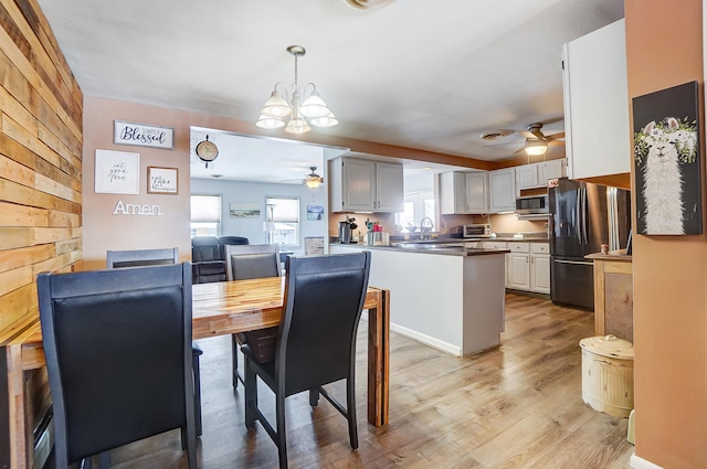 kitchen featuring pendant lighting, dark countertops, stainless steel microwave, freestanding refrigerator, and white cabinets