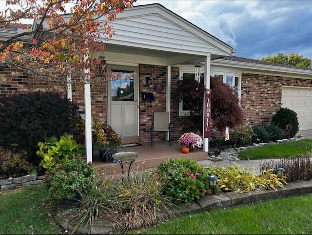 exterior space with an attached garage, covered porch, and brick siding